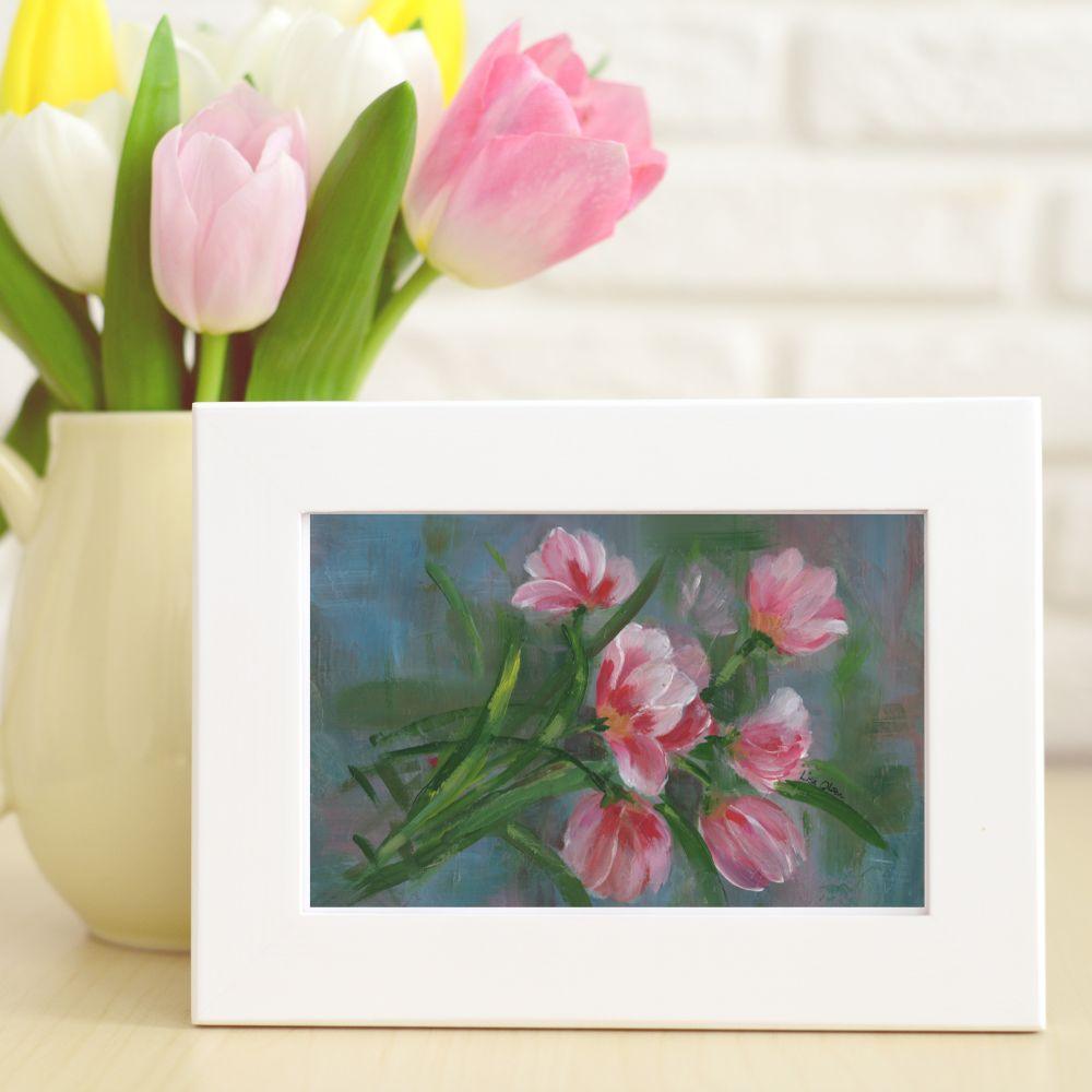 Red and pink tulips greeting card framed in white and displayed horizontally on a tabletop.
