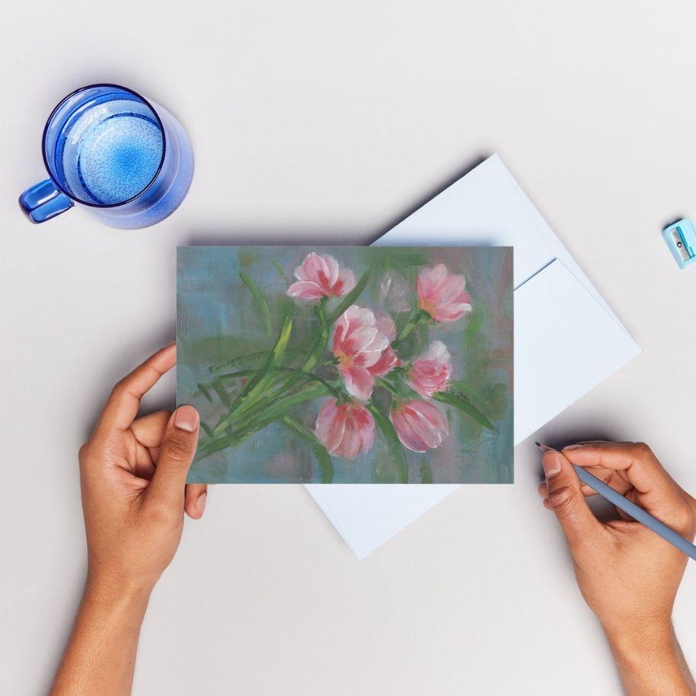 A woman's hands holding a pencil and the Red & Pink Tulips greeting card, ready to write a message.
