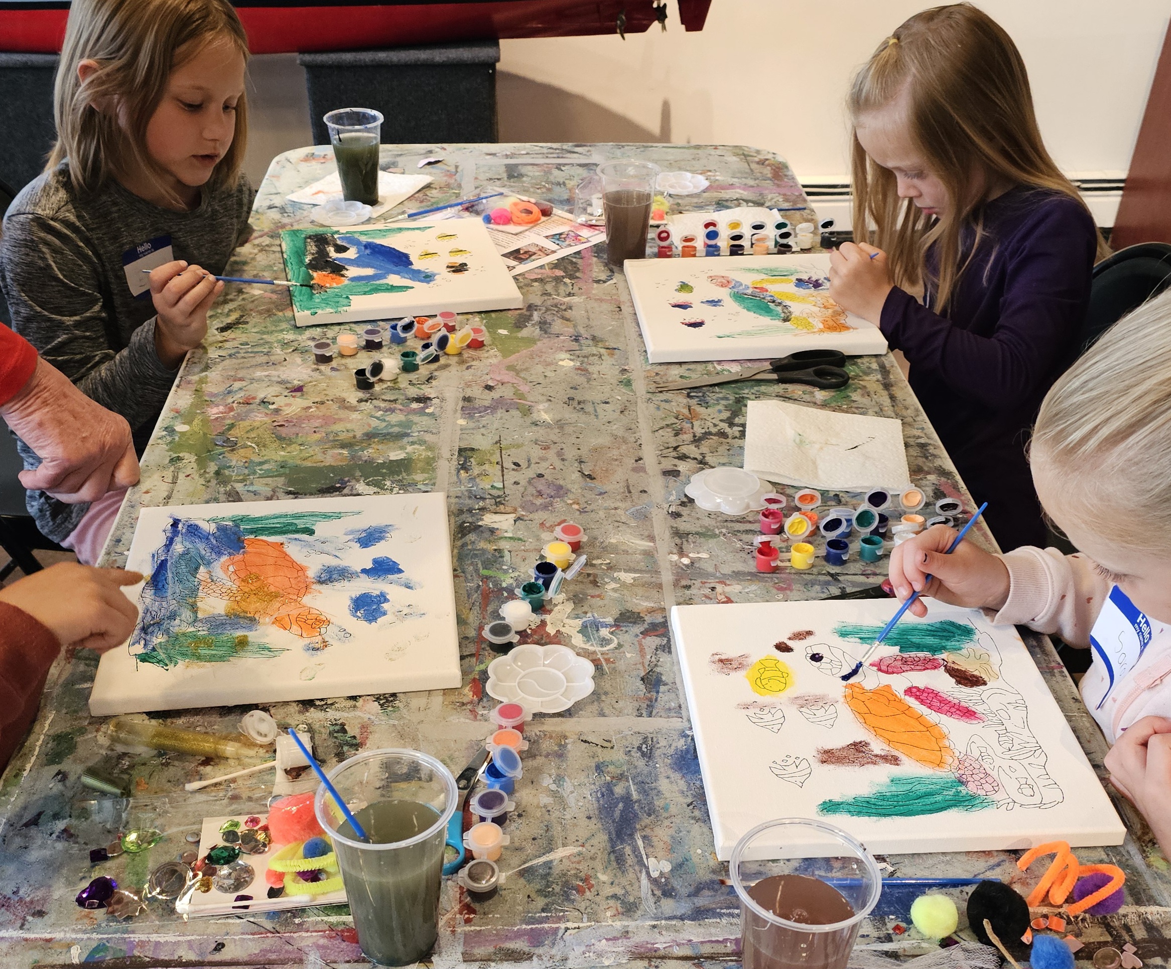 Children painting their turtle canvases at a Creative You art workshop