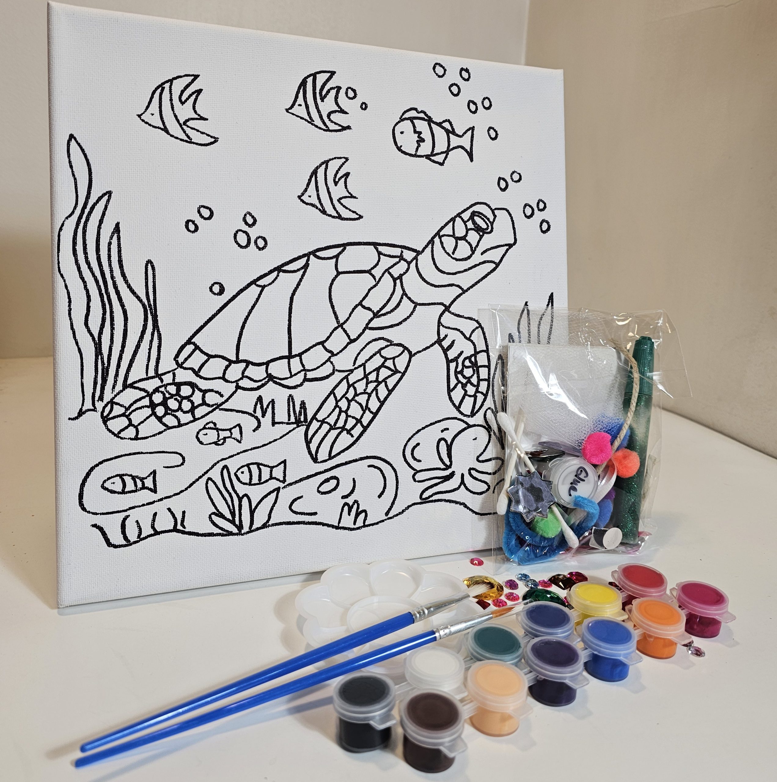 Turtle canvas surrounded by paints, glue, and collage items