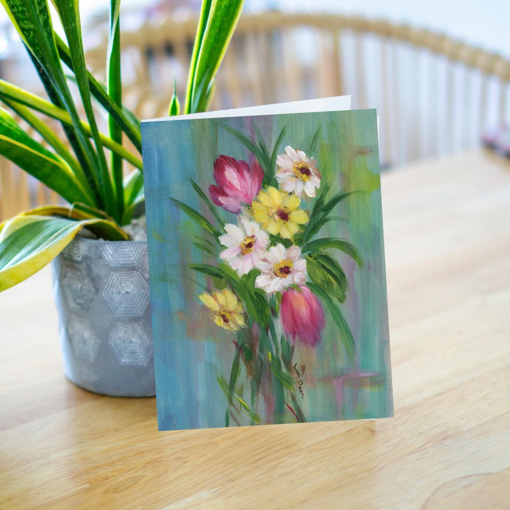 Greeting card with a spring bouquet of tulips and daisies leaning near a plant